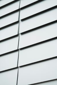 A close-up view of a home exterior with fiber cement and vinyl siding in warm, sunny weather.