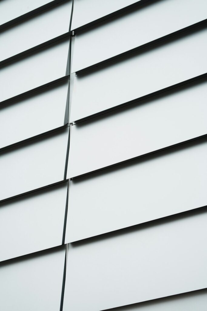 A close-up view of a home exterior with fiber cement and vinyl siding in warm, sunny weather.
