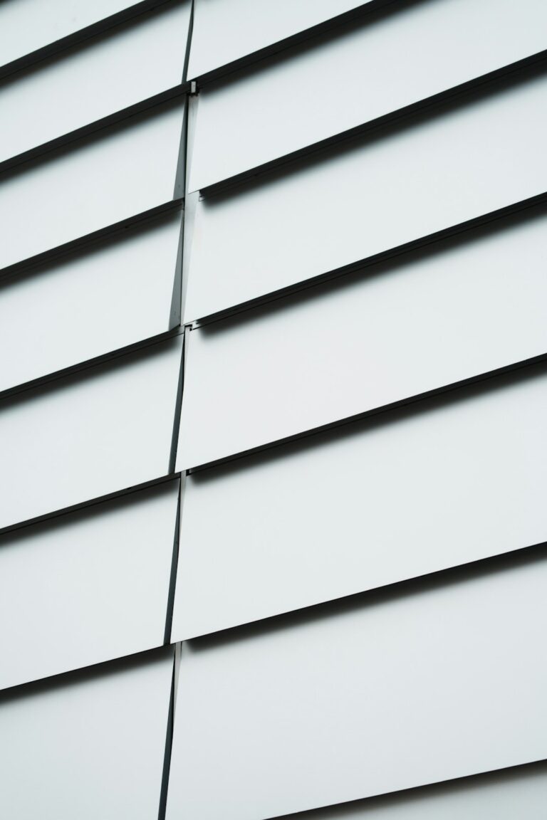 A close-up view of a home exterior with fiber cement and vinyl siding in warm, sunny weather.