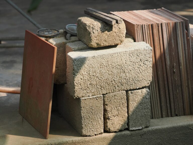 A close-up view of a home’s exterior wall made of brick and stucco alongside a metal roof under strong sunlight.