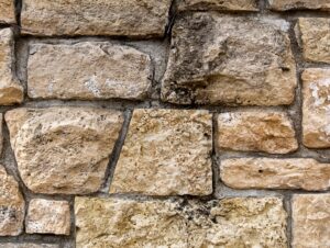 A side-by-side view of a patio built with natural stone and a wall clad in manufactured stone, showing clear texture differences.