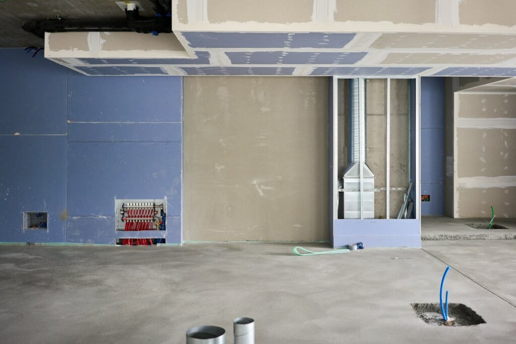 Homeowner reviewing paint and flooring product labels beside open windows during a renovation.